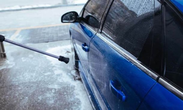 IMage of pressure washer wand washing the side of bright blue car